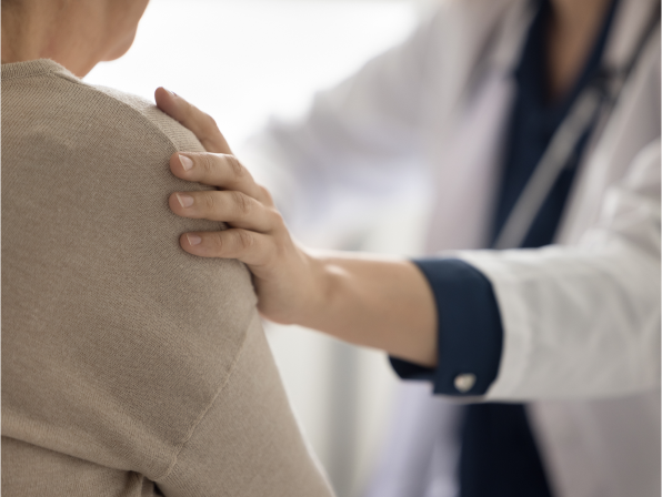 Patient and physician in medical office. Physician putting hand on patient’s shoulder.