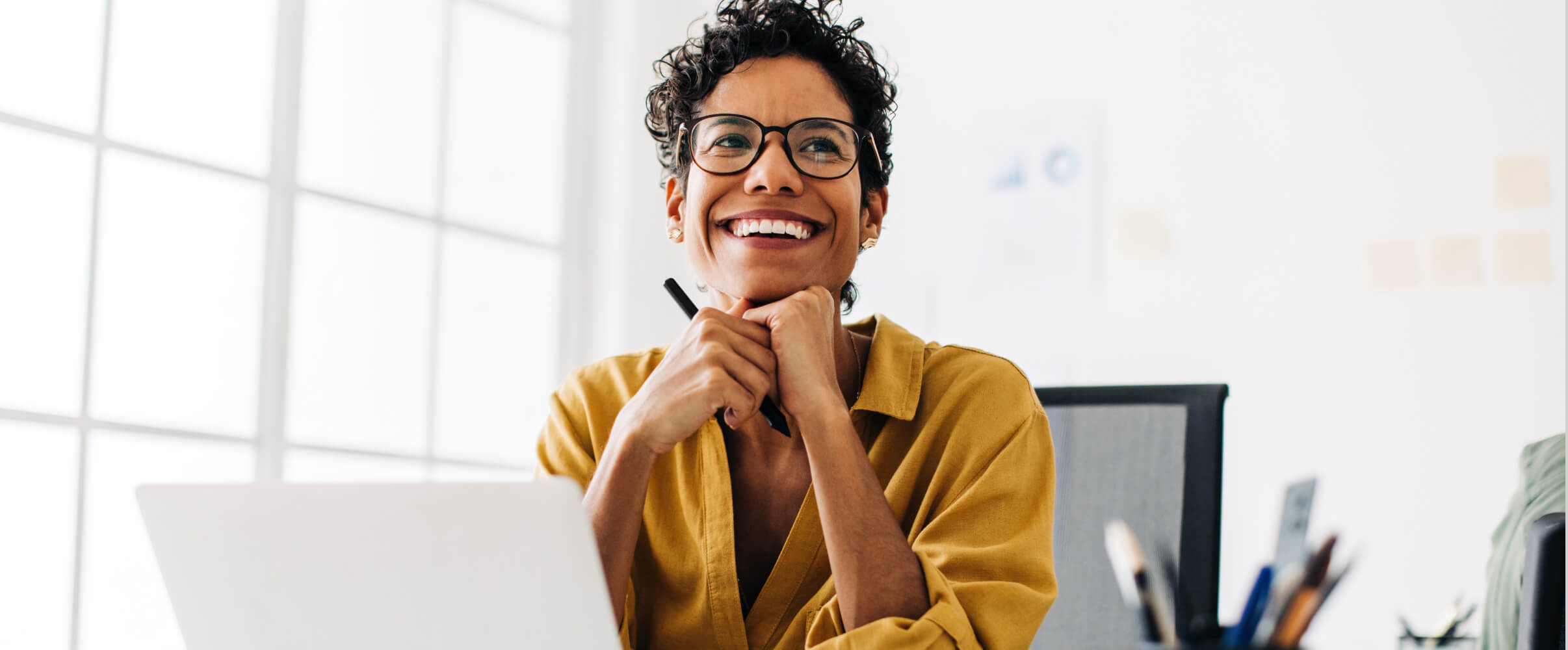 Woman on product development team smiling at laptop in office.