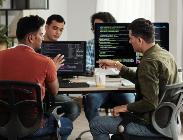 Dedicated software development team sitting around computers and working together.