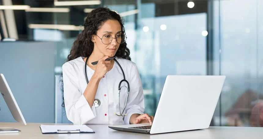 Female doctor with a stethoscope working on a laptop in a hospital office